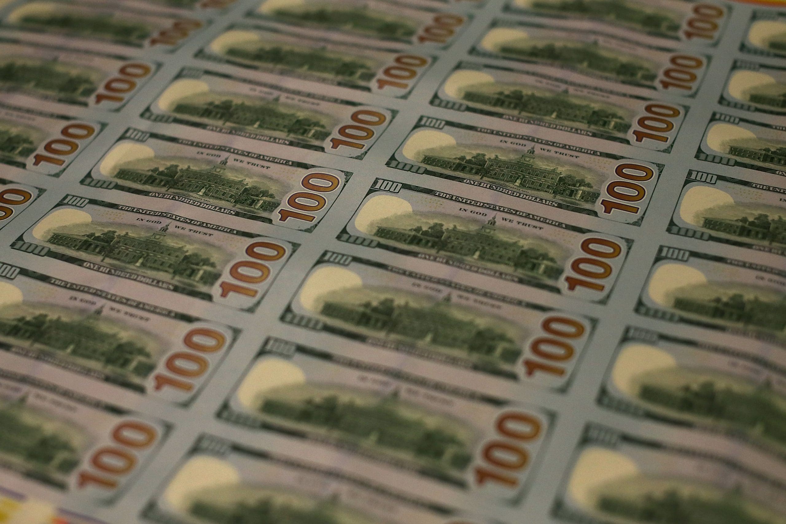 Image of a large stack of freshly minted one hundred dollar bills with the reverse side showing.