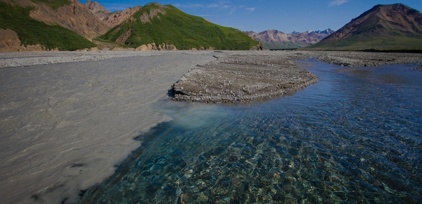 Image of a river running through a valley with mountains in the background.